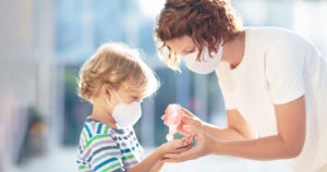 mom and child wearing masks using hand sanitizer